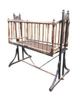 A Edwardian mahogany cot with turned finials and spindle sides, swinging on a trestle stand with