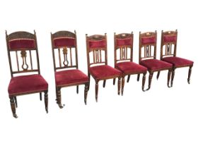 A set of four Edwardian oak dining chairs, the arched backs with pierced heart motifs and foliate