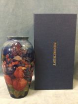 A boxed Moorcroft ovoid tube-lined vase decorated with swallows among apples and berries on blue