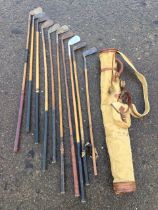 A canvas and leather golf bag containing ten hickory shafted clubs by various makers - Lawson,