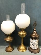 A Victorian brass oil lamp, the reservoir with embossed thistle motif, glass flue and globular glass