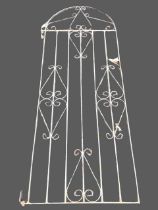 An arched wrought iron garden gate with tubular spindles in rectangular frame with scrolled