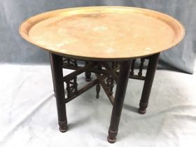 A circular brass coffee table, the tray top with islamic decoration supported on an ebonised base