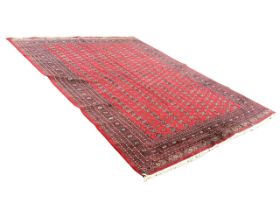 A Pakistan Turkmen style carpet, the red field with eight rows of gul motifs within multiple