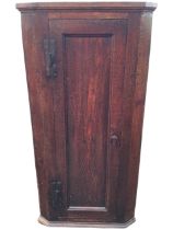 A Georgian oak hanging corner cupboard, the moulded cornice above a panelled door enclosing