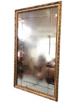 A contemporary mirror, the rectangular plate with bevel cut border in foliate moulded gilt frame. (