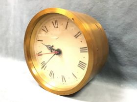 A cylindrical brass cased Gibson electric wall clock by Baume & Co of London, the glazed chapter