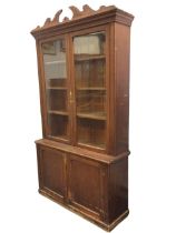 A Victorian stained pine bookcase, the scrolled and fluted swan-neck pediment and moulded cornice
