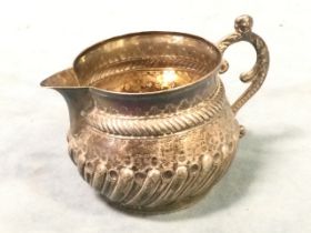 A Victorian hallmarked silver cream jug with gadrooned and punched decoration in 17th century