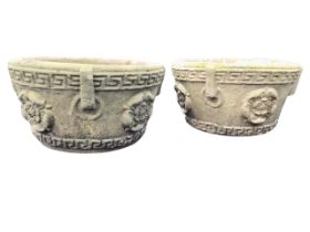 A pair of composition stone garden planters, moulded with rose medallions and faux ring handles,
