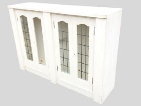 A painted cupboard with four arched faux-leaded glass panelled doors, framed and supported by