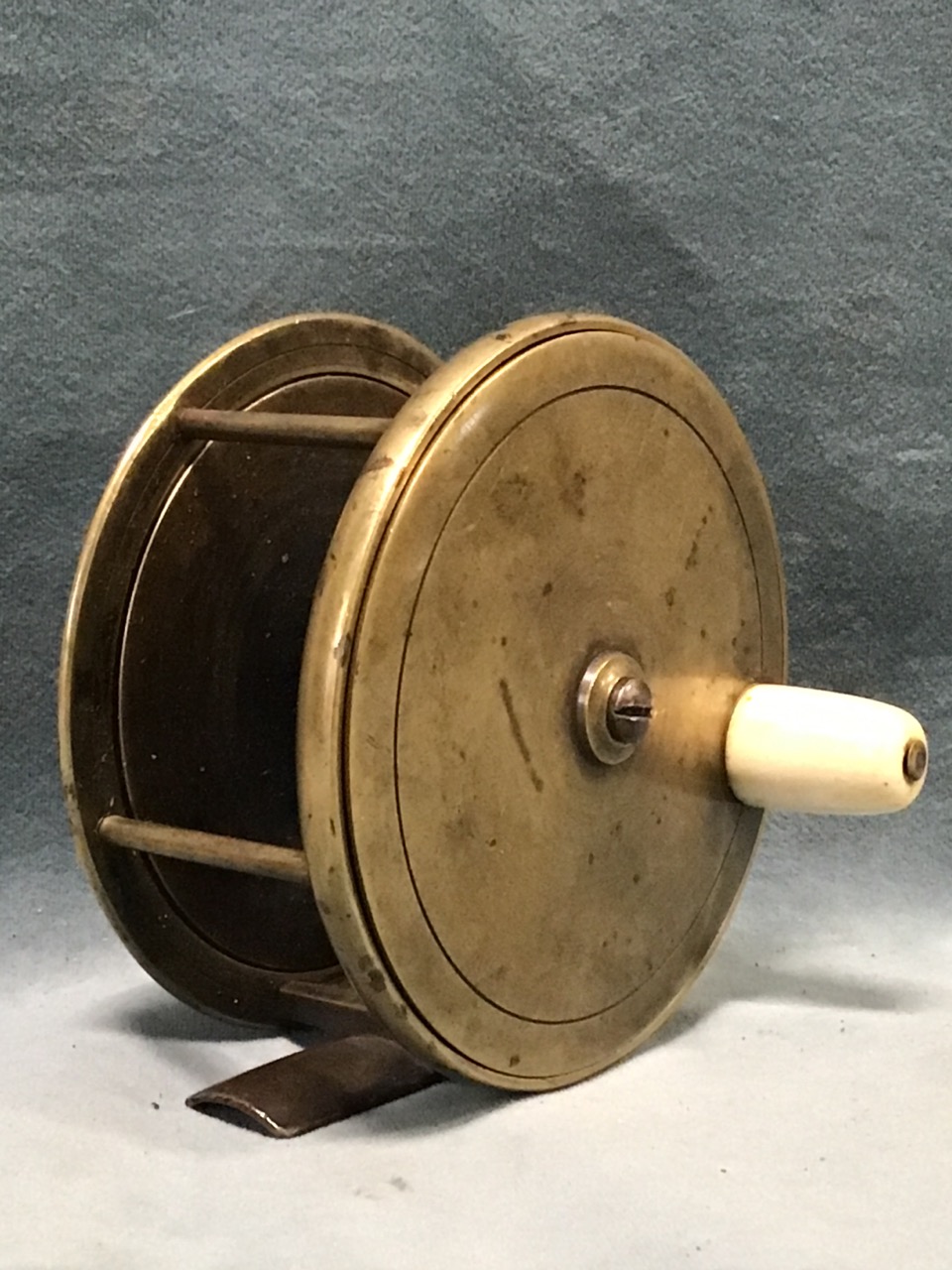 An early Farlows brass salmon fly reel, the drum with four pillars and horn handle, with fish