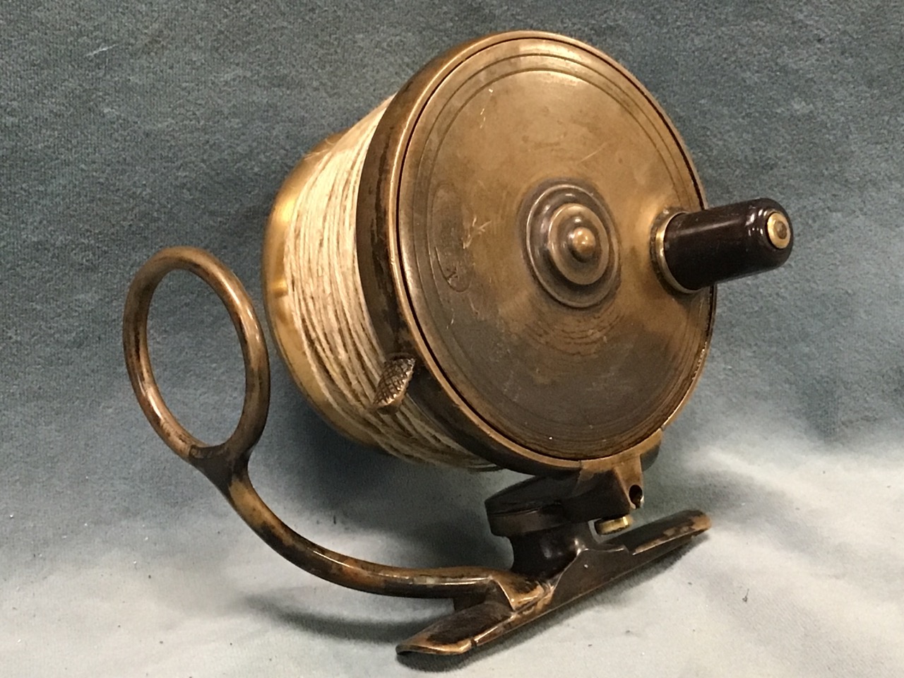 An early Malloch patent brass side casting fishing reel with dished drum and adjustagle line guide