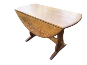 A circular oak drop-leaf dining table, with two leaves opening on brackets, raised on shaped pierced