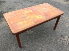 A 70s mahogany coffee table, the rounded rectangular top inset with glazed tiles with fern and