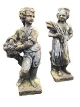 A pair of composition stone garden statues cast in the form of a boy and a girl carrying fruit &