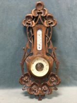 An Edwardian art nouveau walnut framed aneroid barometer, the pierced frame carved with sinuous