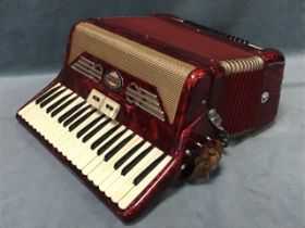 An Italian piano accordion, the red marbled case with three-octave keyboard and leather shoulder