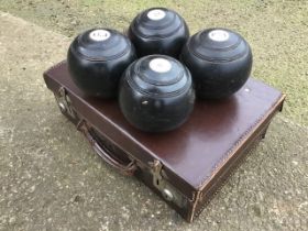 A set of four ebonised lawn bowls with inlaid numbered and initialled discs, in a leather case