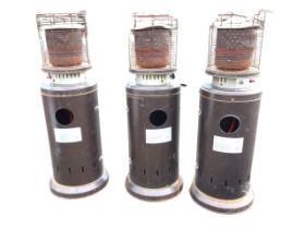 A set of three garden patio heaters, the tubular stoves on stands with hinged doors for cylinders,