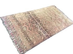 A Baluchi rug, the dusty pink field with rows of hooked lozenge motifs within multiple scroll and