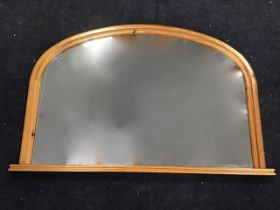 A reproduction pine Victorian style arched overmantle mirror, the moulded frame on rectangular