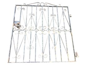 A wrought iron garden gate, the scrolled crest above a rectangular panel of vertical bars