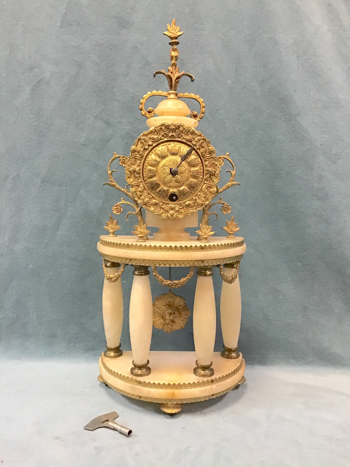 An alabaster and gilt brass portico mantel clock, the domed top with flame and scrolling foliate