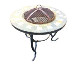 A circular garden patio fire with tiled tabletop border on scrolled legs framing grill burning