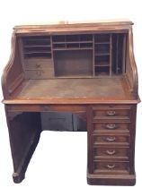 A C19th American mahogany roll-top desk, the rectangular tambour opening to pigeonholes and drawers,