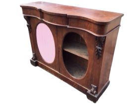 A Victorian mahogany side cabinet, the serpentine top and conforming frieze above a pair of oval