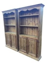A pair of Victorian style pine bookcases with moulded cornices and shaped apron above adjustable
