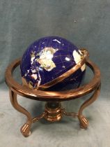 A copper framed globe, the countries formed from polished semi-precious stones on blue lustre