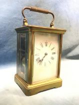 A French brass carriage clock, the swing handle above a rounded rectangular bevelled glazed panel,