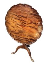 A George III mahogany tea table, the circular piecrust top tilting on a baluster turned column,