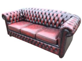 A leather upholstered three-seater chesterfield sofa, the buttoned back and outscrolled arms