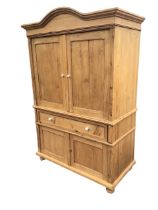 A Victorian style pine cabinet, the arched cornice above a pair of panelled doors opening to shelved