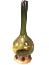 An unusual olive glass bottle vase with tall neck above a bulbous body mounted on a copper base