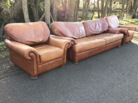 A leather three-piece suite with deep cushions and outscrolled arms with brass studding, the