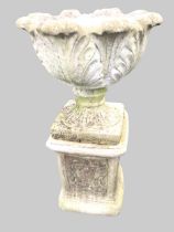 A composition stone urn on stand with leaf cast pot having square plinth base, set on an