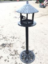 A painted metal garden birdtable with circular ribbed pitch roof above a hexagonal pagoda style