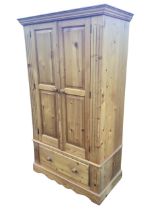 A Georgian style pine wardrobe with moulded cornice above a pair of fielded panelled knobbed