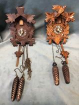 Two contemporary Swiss Cottage type cuckoo clocks with fircone weights, roman chapters and leaf