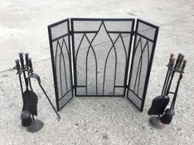 A gothic style three-panel folding steel mesh fire guard; and a pair of iron fireside companion sets