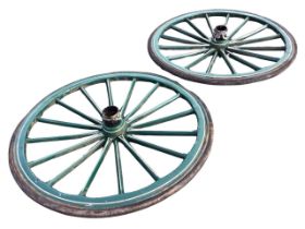 A pair of painted elm cart wheels having central hubs and scalloped rims joined by shaped spokes,