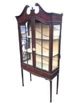 An Edwardian mahogany display cabinet, the swan-neck pediment with urn finial above arched