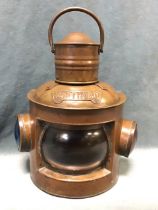A brass masthead lantern with swing handle and cylindrical chimney above a semicircular case with