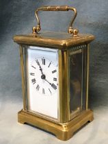 An Edwardian brass carriage clock in architectural style case framing bevelled glass panels, the