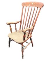 A Victorian armchair, the arched toprail above a spindle back and solid dished seat, flanked by
