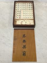 A cased Chinese mahjong set with coloured tiles, counters and sticks, the box with sliding lid. (